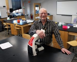 新闻 13 Dr. John Bohmfalk in a lab with a microscope.