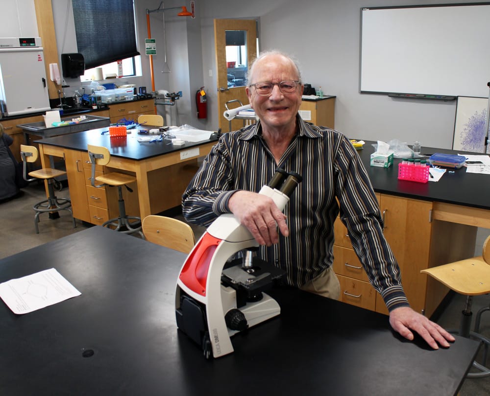 Dr. John Bohmfalk in a lab with a microscope.